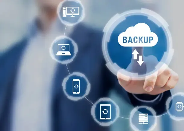 Homem apontando para ícone de nuvem com a palavra Backup, conectado a dispositivos como servidores, laptops e smartphones.